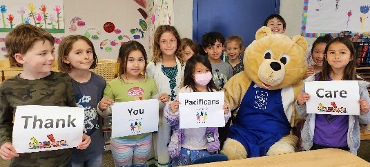 Children with the bear mascot holding signs that read Thank You Pacificans Care