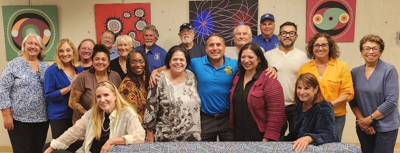 Pacificans Care board members and Pacifica social service agency directors posing together in front of a colorful mural