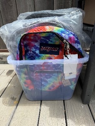 Donated backpacks packed in a clear storage bin